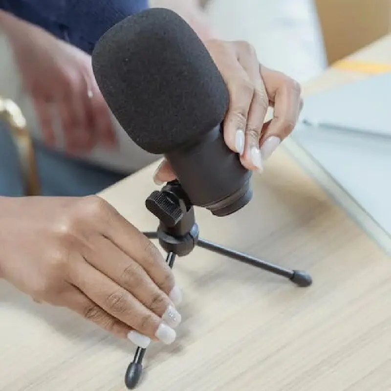 A person holding a microphone on top of a table.